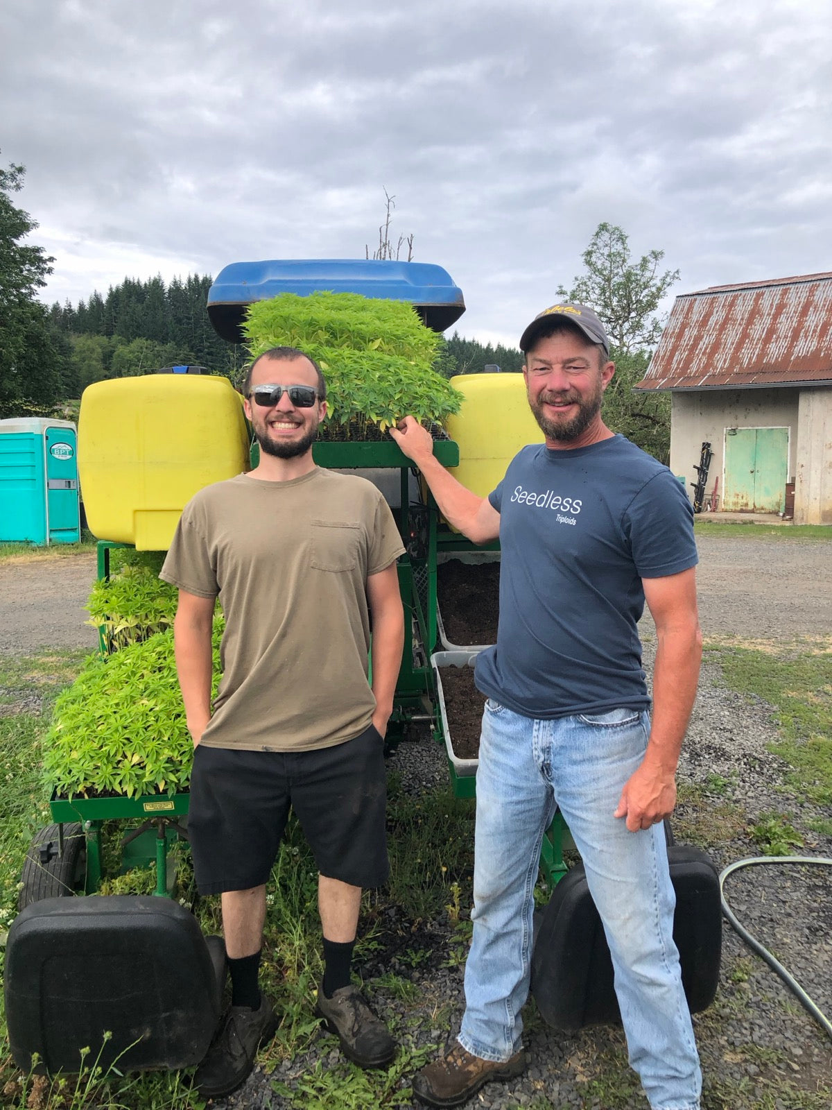 Sterling and Marty beside the tractor and planter with trays of hemp starts.